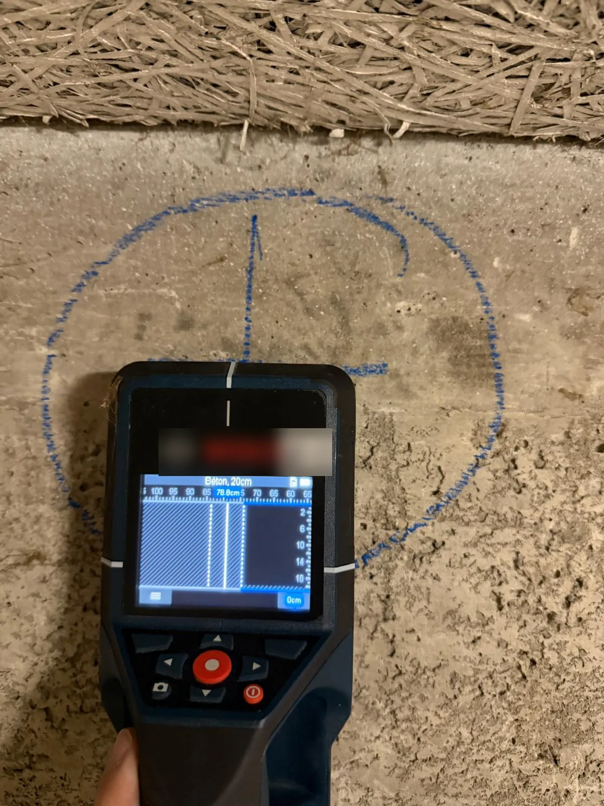 Scanner de béton contrôlant un emplacement de carottage tracé en bleu sous le plafond isolé d'un sous-sol