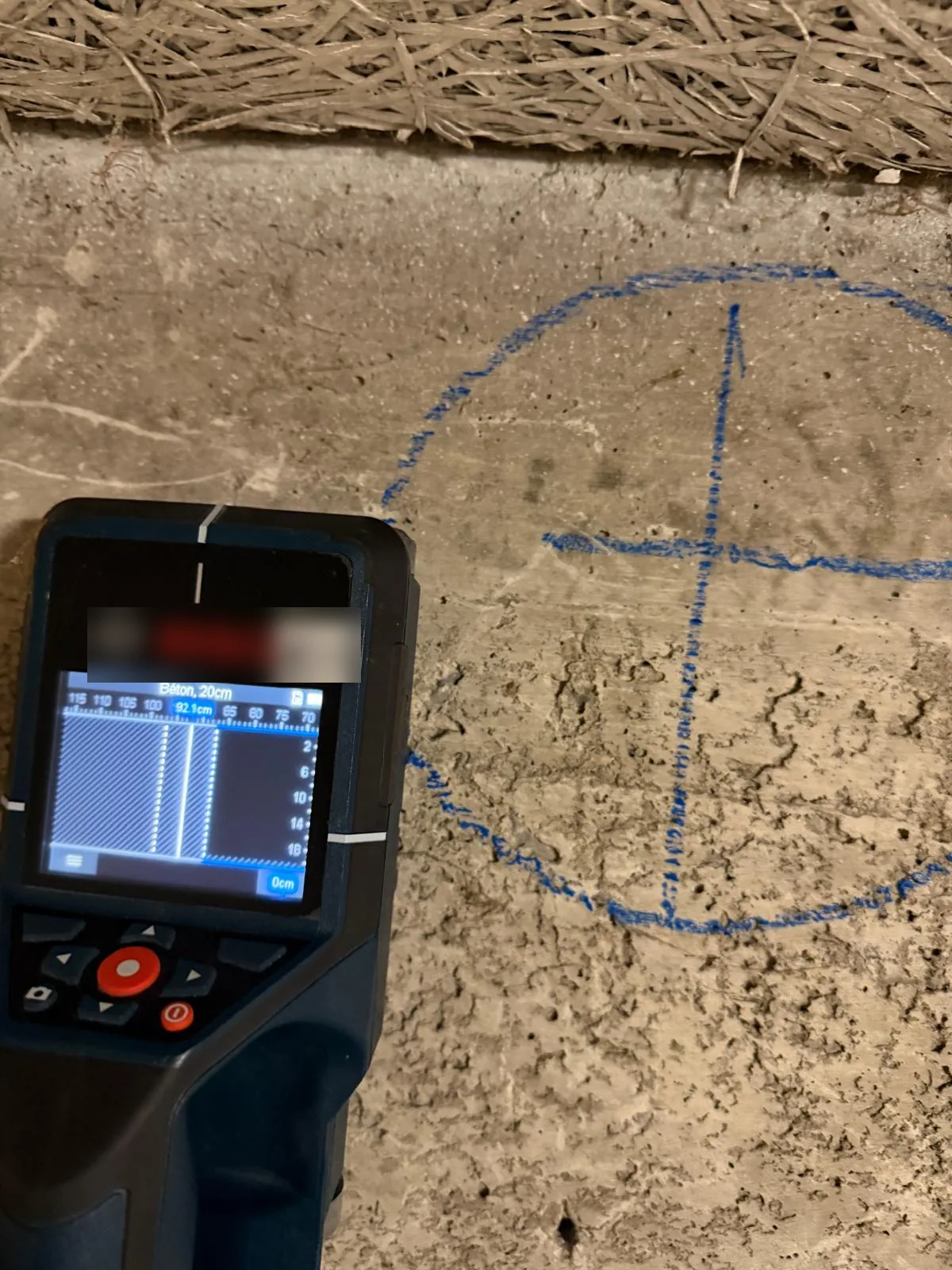 Marquage d'un carottage au crayon bleu avec cercle et axes, à côté d'un scanner de béton