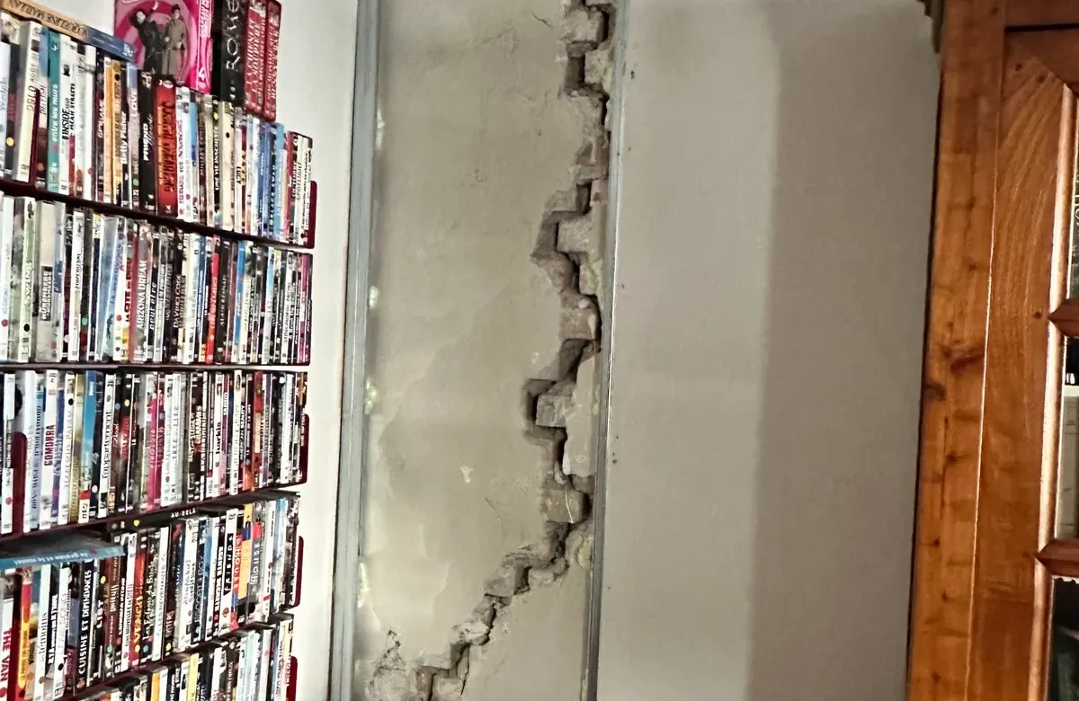 Fissure en escalier dans un mur en briques, enduit déposé pour l'expertise