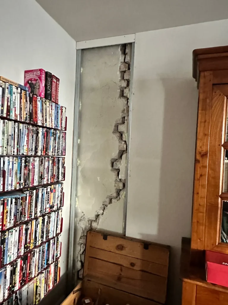 Fissure en escalier dans un mur en briques, enduit déposé pour l'expertise