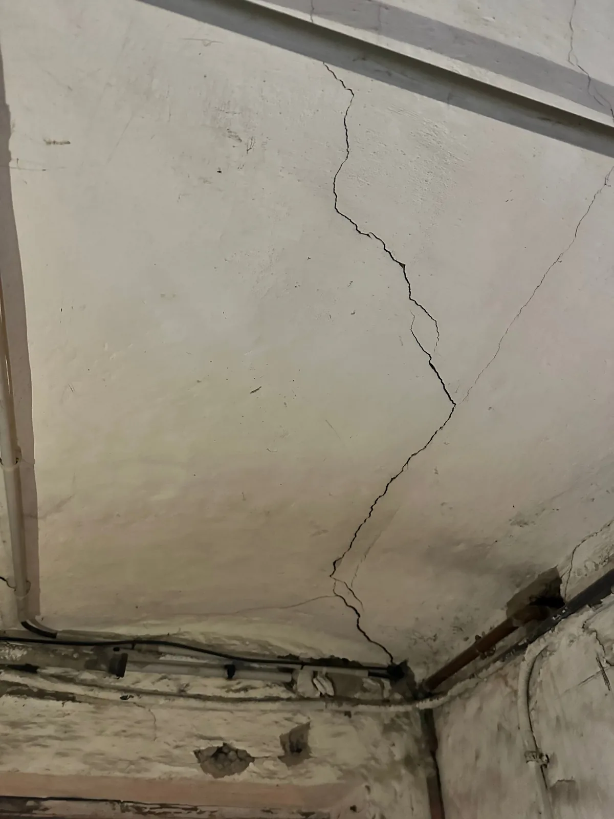 Fissures au plafond d'une cave, dans le prolongement des fissures du mur