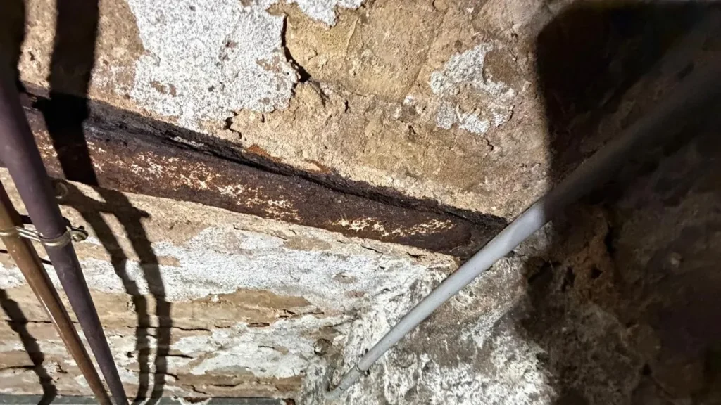 IPN rouillé cave : poutre métallique corrodée au contact d'un mur humide