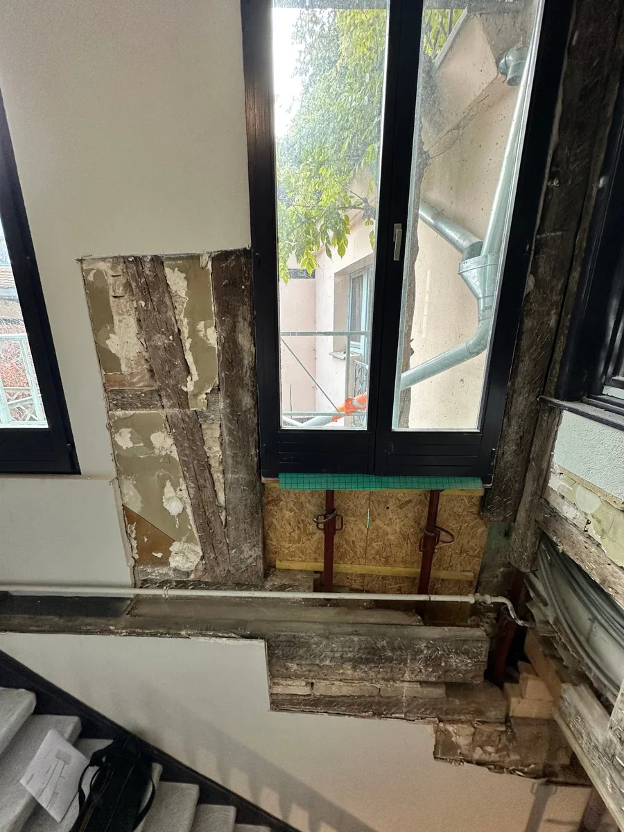 Pan de bois ouvert dans une cage d'escalier, étais sous l'allège et descente d'eau pluviale visible par la fenêtre