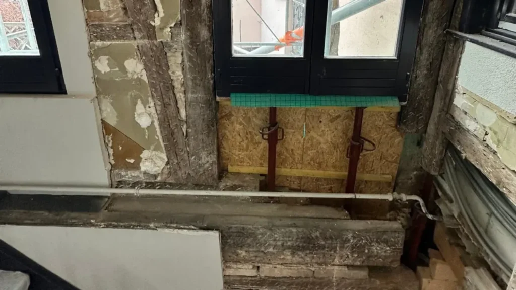 Pan de bois dégradé par une infiltration d'eau, ouvert et étayé dans une cage d'escalier