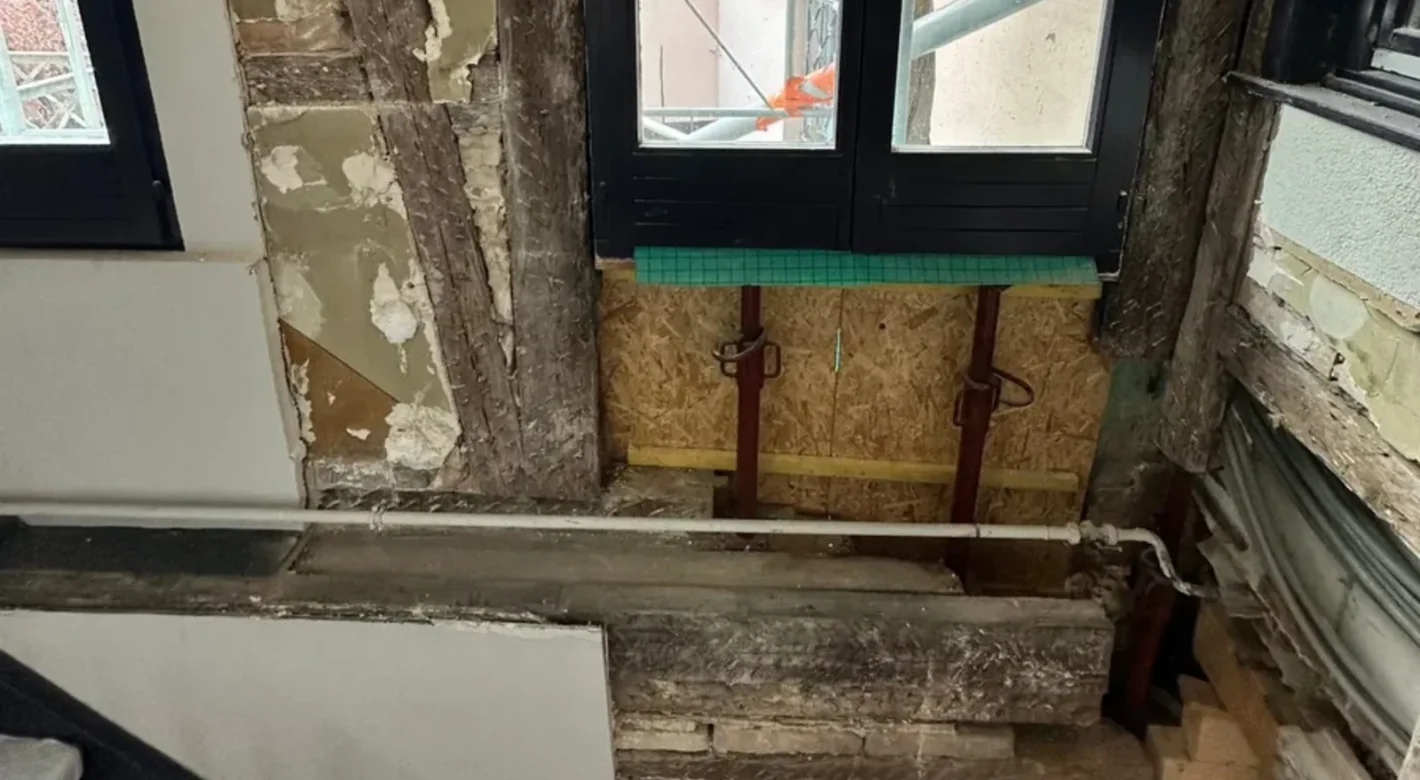 Pan de bois dégradé par une infiltration d'eau, ouvert et étayé dans une cage d'escalier