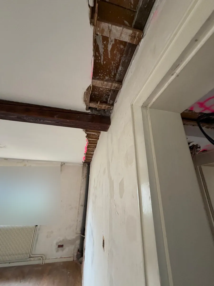 Plafond ouvert le long d'un mur montrant une poutre bois apparente et les solives du plancher