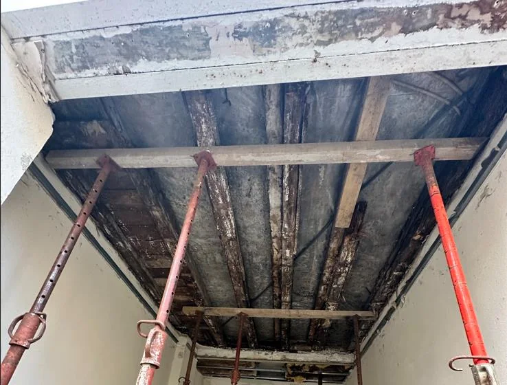 Plancher bois étayé par des étais métalliques sous le porche d'un immeuble ancien