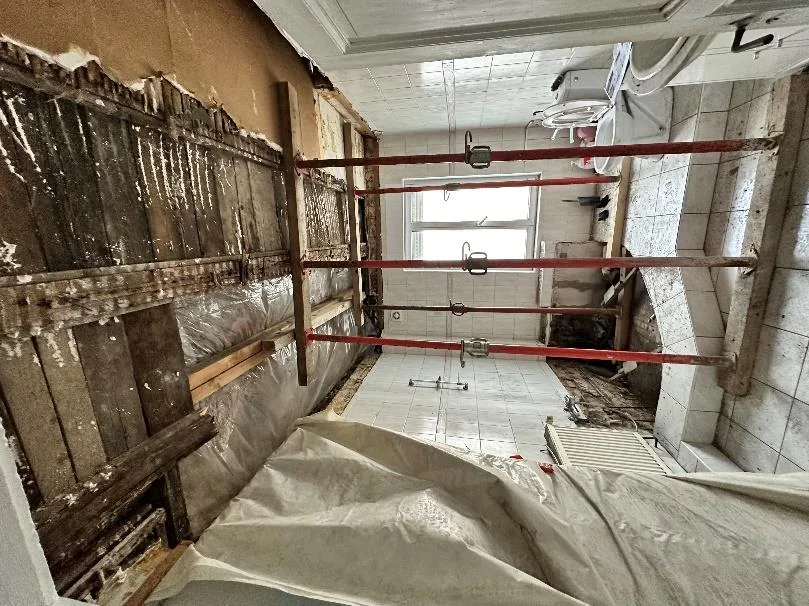 Plancher bois étayé et ouvert dans une salle de bain d'immeuble, solives dégradées