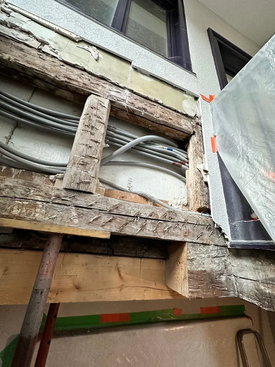 Pièce de bois neuve mise en place sous une poutre ancienne de pan de bois