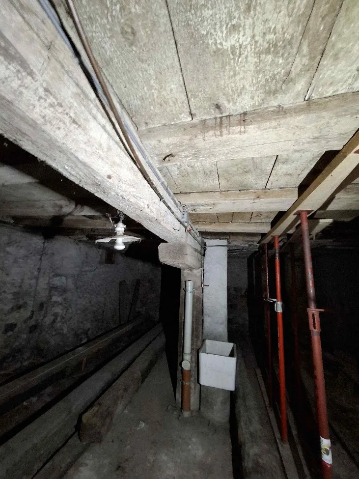 Poutre maîtresse en bois d'un sous-sol portant les solives et les colombages des étages