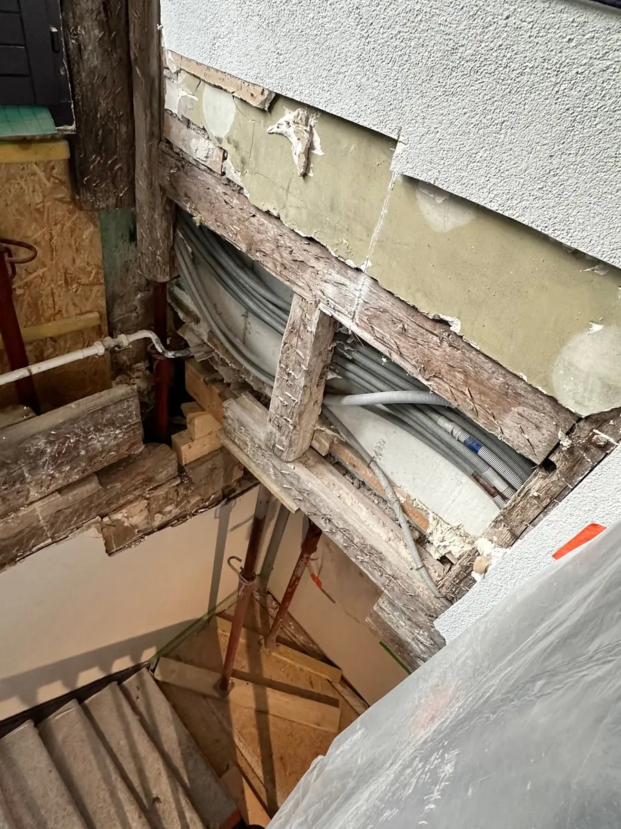 Poutres et poteaux d'un pan de bois dégradés par l'eau dans une cage d'escalier