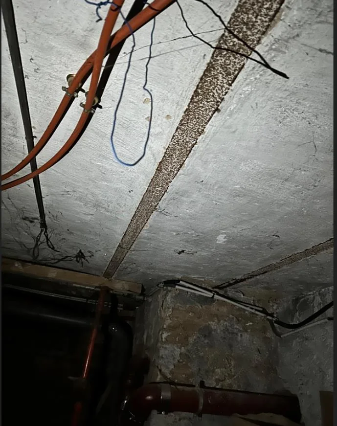 Plafond de sous-sol avec poutrelles en acier corrodées dans un immeuble ancien