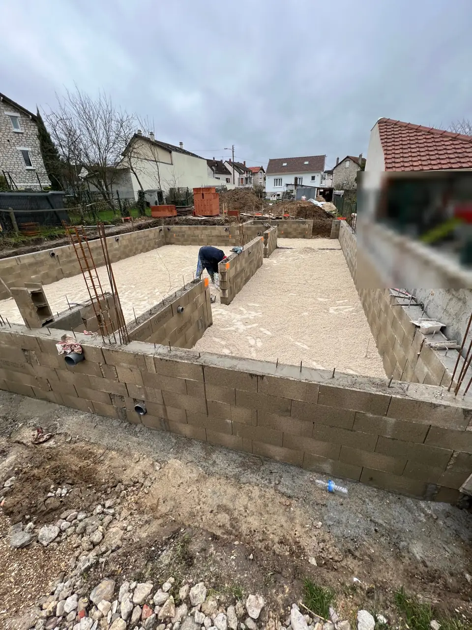Fondations de maison : murs de vide sanitaire en blocs béton montés sur les semelles, hérisson de gravier à l'intérieur